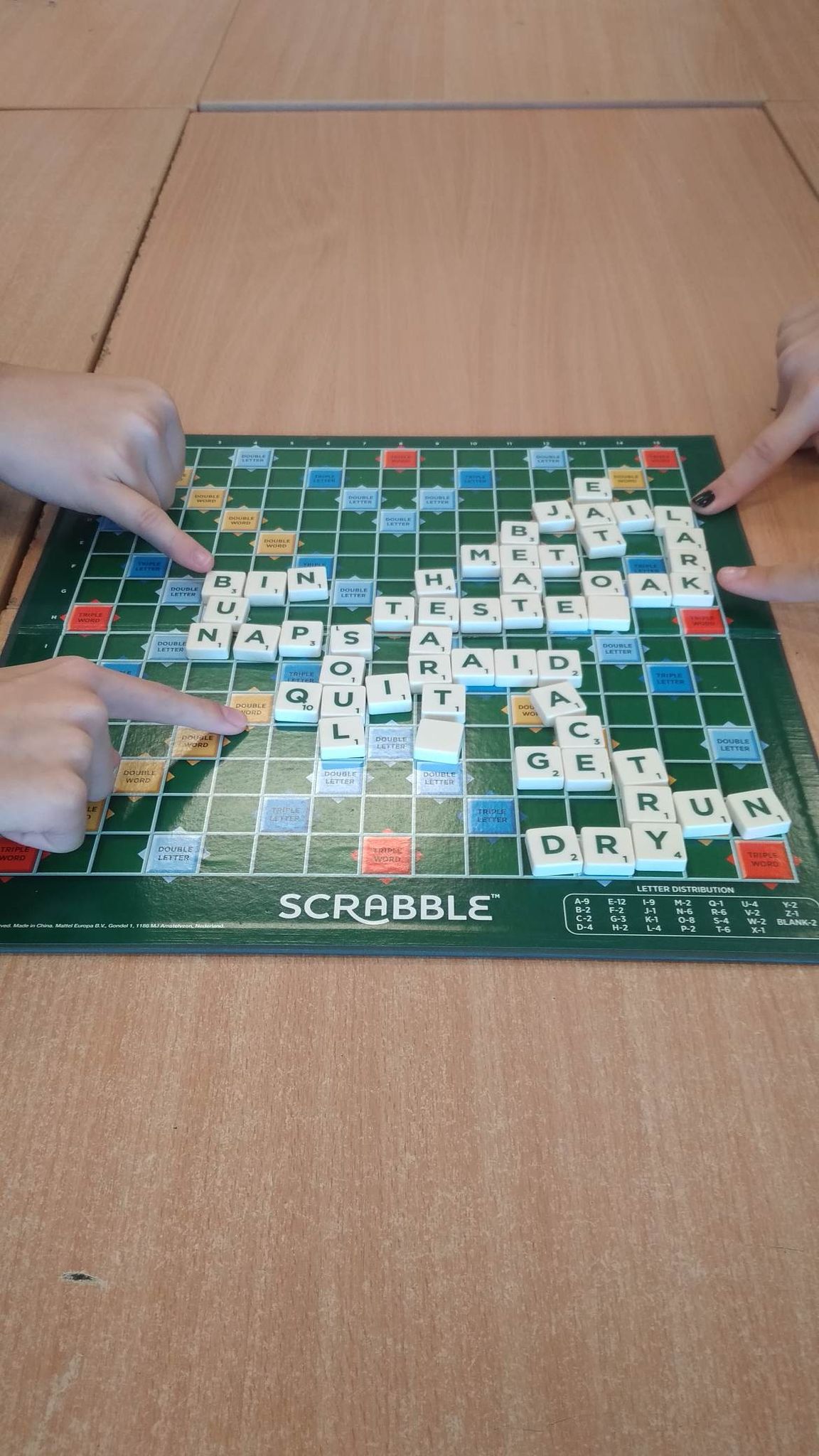 plansza do Scrabble i wskazujące palce uczniów